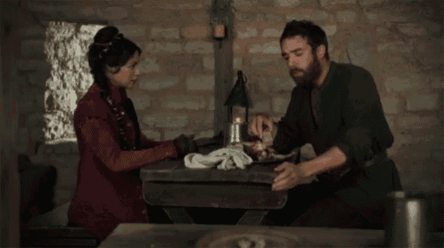 a man and a woman sit at a table eating