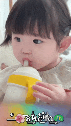 a little girl drinking from a yellow and white bottle with the name sherita on the bottom right
