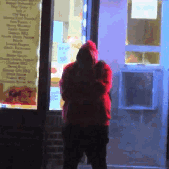 a man in a red hoodie is standing in front of a store with a sign that says ' fried chicken '