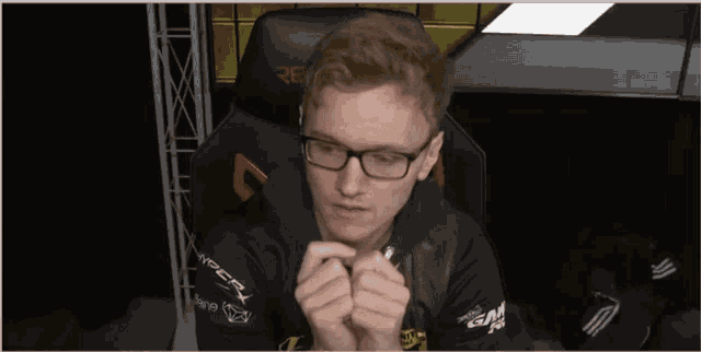 a man wearing glasses is sitting in a chair that says re on it