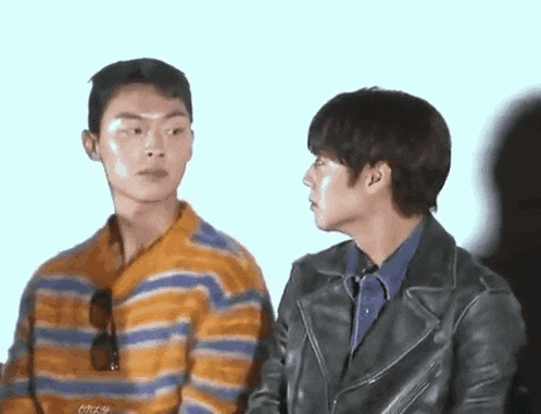 two men are standing next to each other and looking at each other .