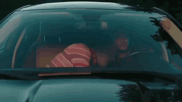 a man driving a car with a pillow on the back seat