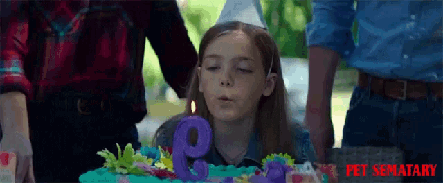 a little girl blowing out a number 9 candle