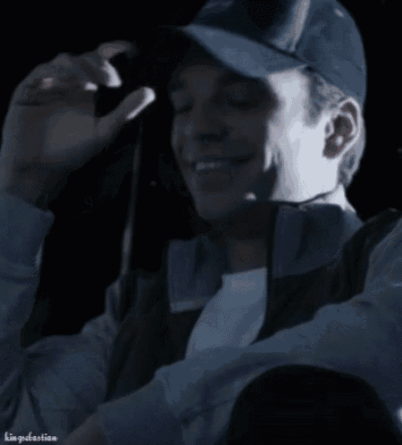 a man wearing a baseball cap is smiling in the dark with the name kingsebastian below him