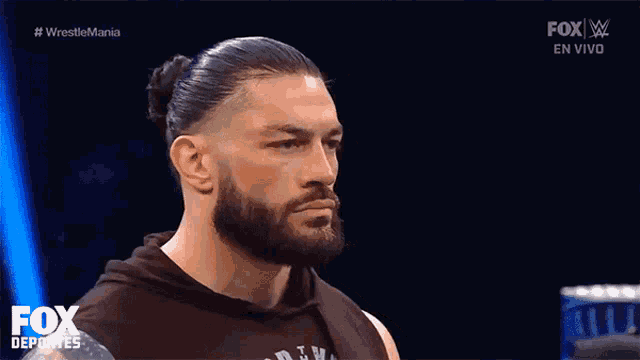 roman reigns is a wrestler with a beard and a bun on his hair .