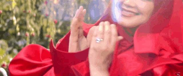 a woman in a red dress is wearing a ring on her finger and smiling .