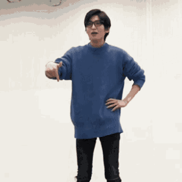 a man in a blue sweater and glasses is pointing at something