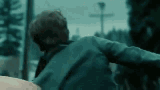 a man in a blue jacket is standing in a dark room .