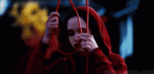 a woman in a red hood is holding a red string in her hand .