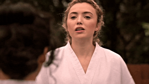 a woman in a white karate uniform is standing in front of another woman