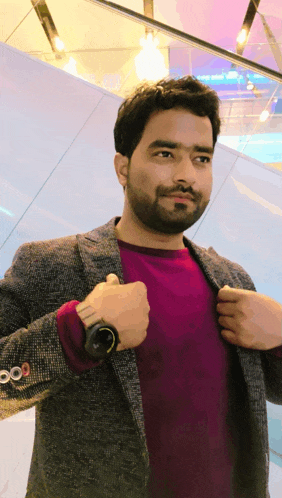 a man wearing a jacket and a purple shirt is adjusting his jacket buttons
