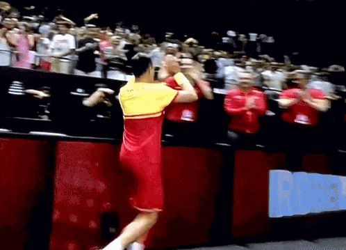 a man in a red and yellow shirt is jumping in the air
