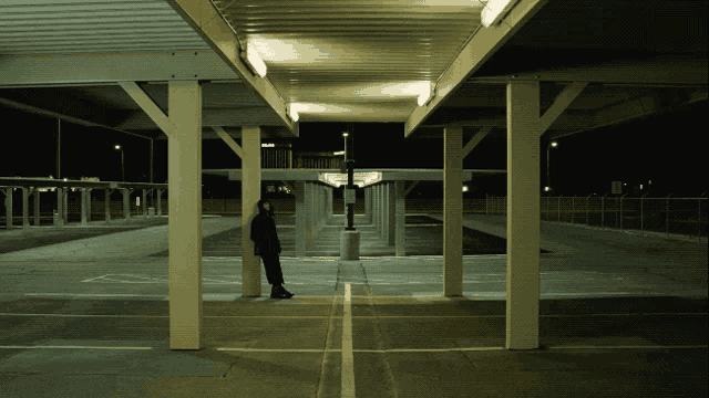 a person standing in an empty parking garage with a sign that says no parking