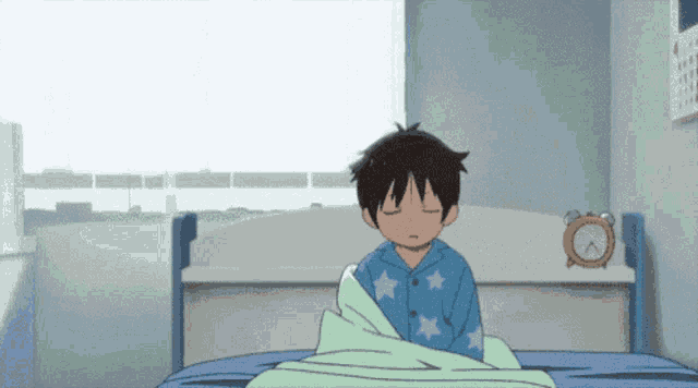 a boy is sitting on a bed with his eyes closed and an alarm clock behind him