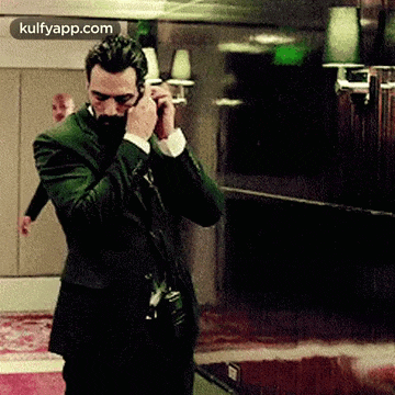 a man in a suit is talking on a cell phone