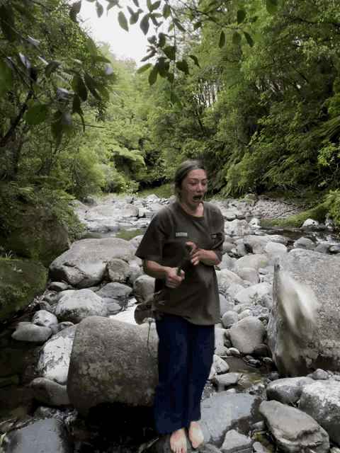 a person standing on a rock in a stream with a shirt that says columbia on it