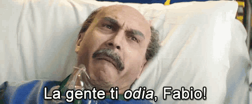 a bald man with a mustache is laying in a hospital bed with the words la gente ti odia fabio