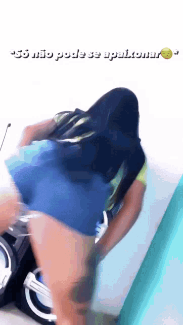 a woman in shorts is dancing in front of a speaker with the words " so não pode se apaixonar " on the bottom