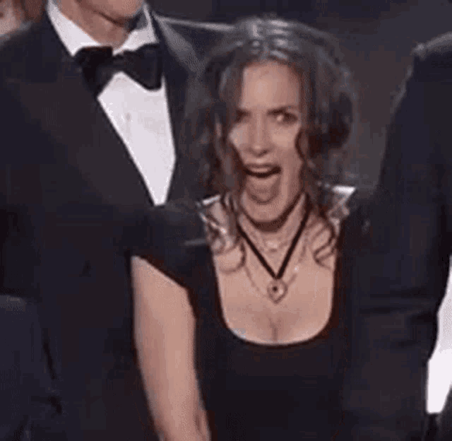 a woman in a black dress is making a funny face with her mouth open .