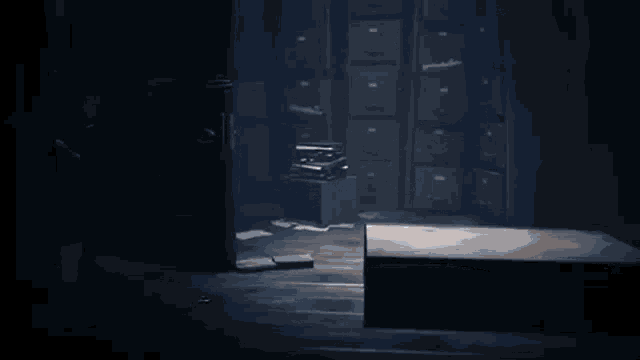 a dark room with a stack of filing cabinets and a wooden box .