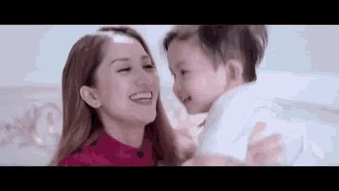 a woman is holding a baby in her arms and smiling at the baby .