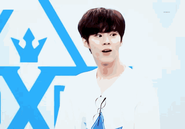 a young man wearing glasses and a white shirt stands in front of a blue triangle and the letter p.