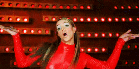 a woman in a red top is standing in front of a wall of red lights .