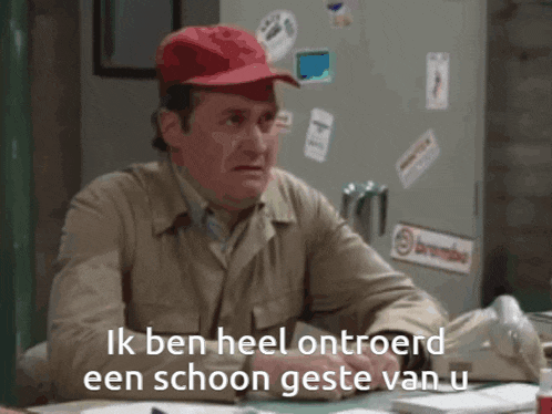 a man wearing a red hat sits at a desk with the words ik ben heel ontroerd een schoon geste van u