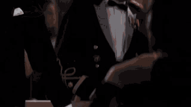 a man in a tuxedo and bow tie is standing next to another man in a tuxedo and bow tie .