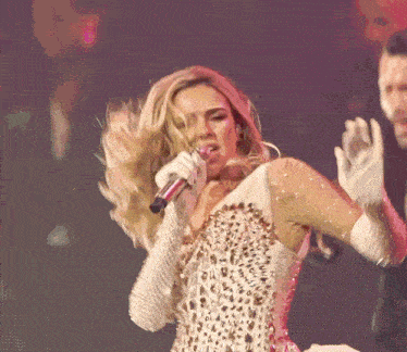a woman singing into a microphone while wearing a leopard print dress