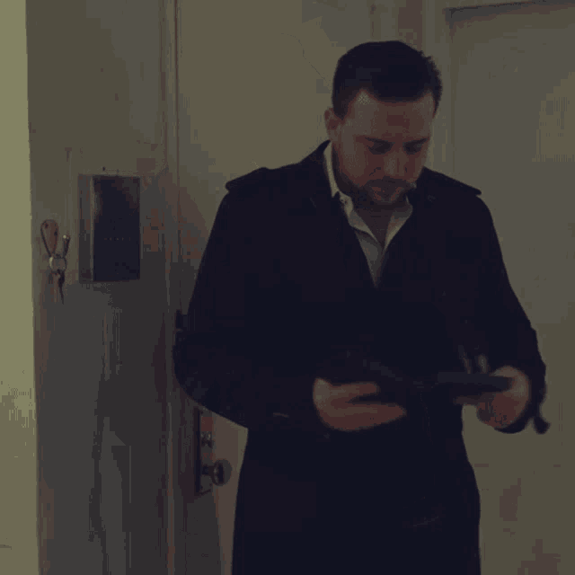 a man in a suit is standing in front of a door with a key hanging on it