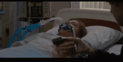 a woman with an oxygen mask on her face is laying in a hospital bed