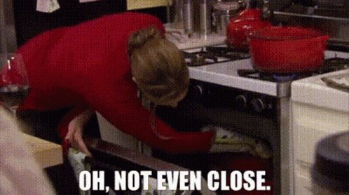a woman is reaching into an oven with the words `` oh , not even close . ''