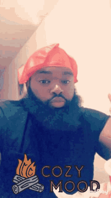 a man with a beard is wearing a red hat with the words cozy mood written on it .