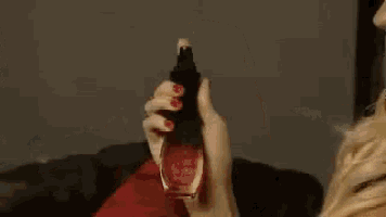 a woman is sitting on a couch with a red pillow and holding a ring .