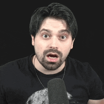 a man with a beard is talking into a microphone and making a funny face