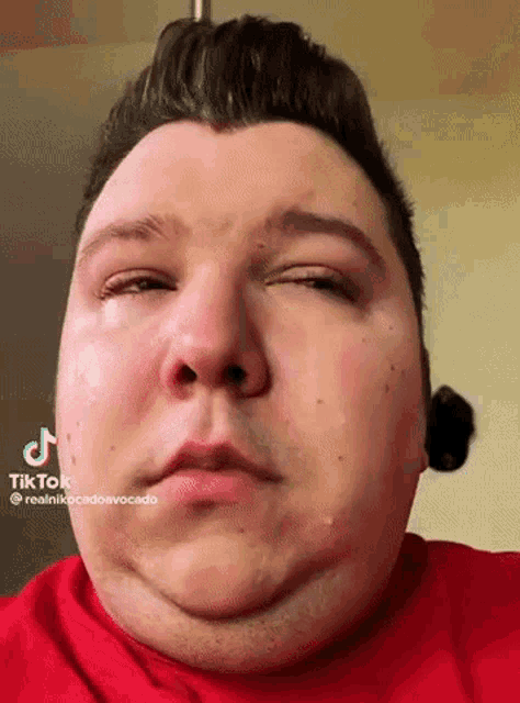 a close up of a man 's face with a red shirt on .