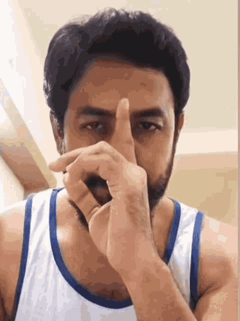 a man with a beard is covering his nose with his finger