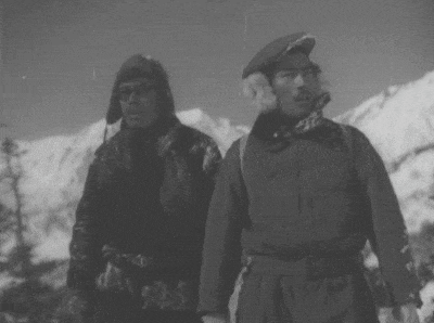 two men standing next to each other in front of a snowy mountain