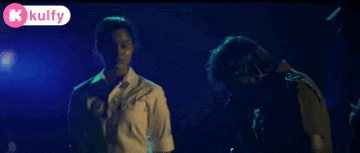 a couple of men are standing next to each other in a dark room with police lights in the background .