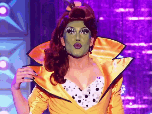 a drag queen wearing a mask and a yellow jacket