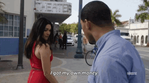 a woman in a red dress is standing next to a man in a blue shirt and says i got my own money .