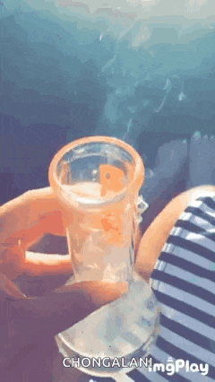 a person is holding a glass of water in their hand