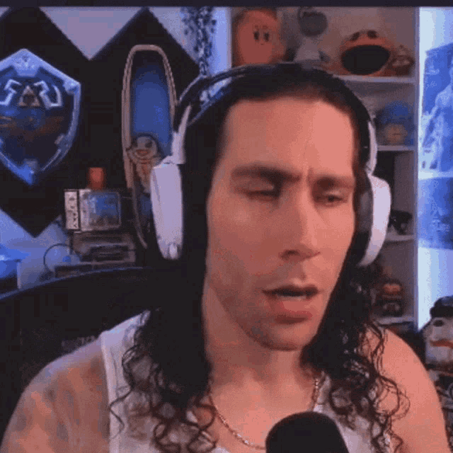 a man wearing headphones is talking into a microphone in front of a wall with a zelda shield on it