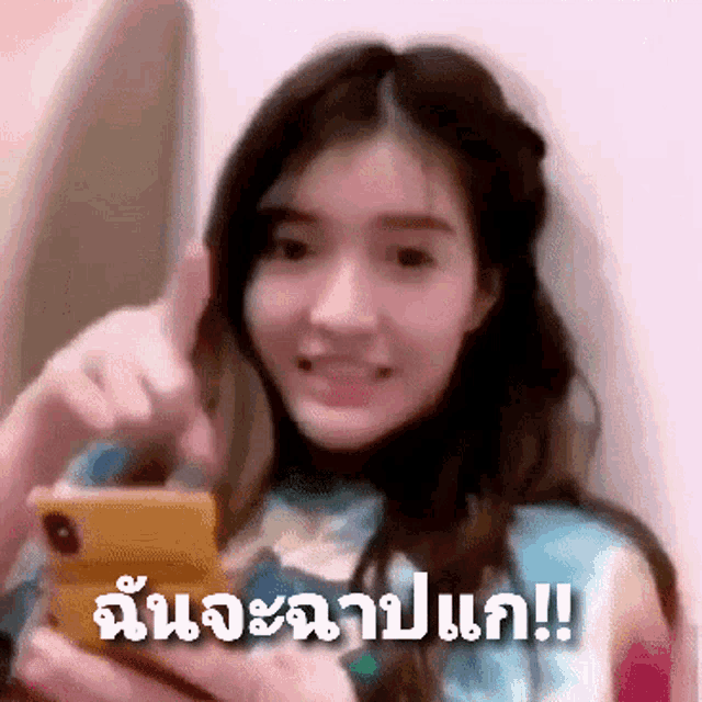 a woman is holding a cell phone and pointing at it in a blurry photo with foreign writing on it