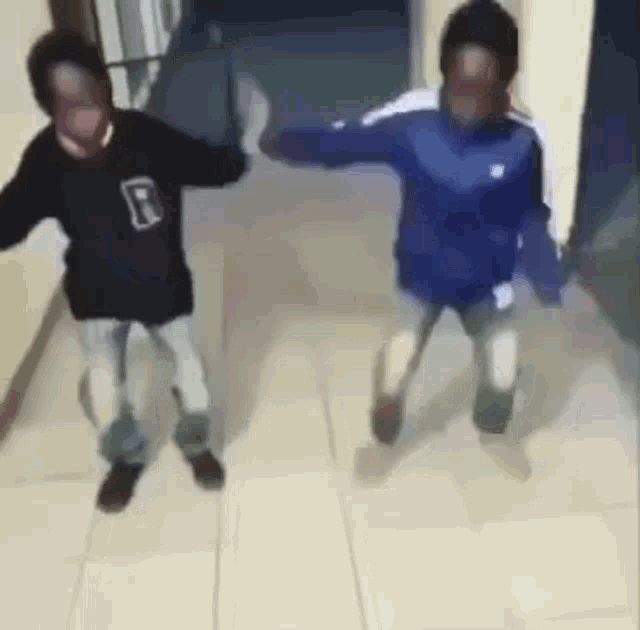 two young boys are dancing in a hallway .