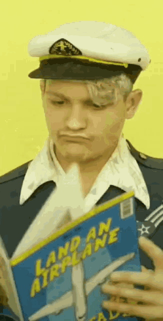 a man in a captain 's hat is reading a book called land an airplane