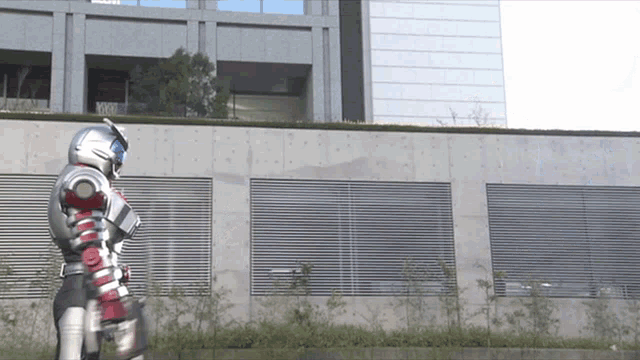 a man in a superhero costume is walking in front of a building