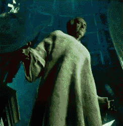 a man in a white robe is holding a knife in a dark room