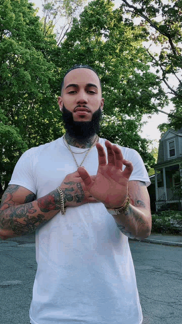 a man with a beard is wearing a white shirt and gold chains